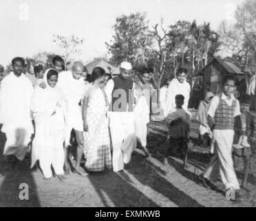 Mahatma Gandhi supported Amtus Salam Abha Gandhi walkingwth Sachin Mitra others through fields riot effected Noakhali Bengal Stock Photo