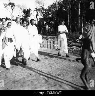 Mahatma Gandhi ; supported by Amtus Salam ; walking with others through fields riot effected Noakhali East Bengal Stock Photo