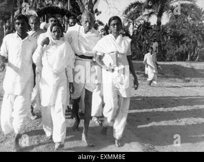 Mahatma Gandhi ; supported Amtus Salam and Manu Gandhi ; walking with others through the riot effected Noakhali East Bengal Stock Photo