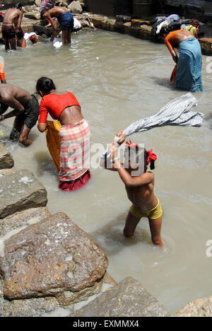 A girl child worker wash clothes in dirty waters at Dharavi in Bombay now Mumbai ; Maharashtra ; India Stock Photo