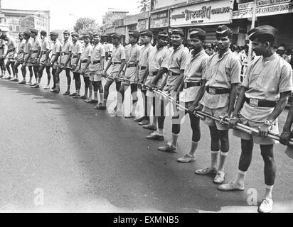 Police constables standing hand in hand in one line holding batons Bombay Mumbai Maharashtra India Stock Photo
