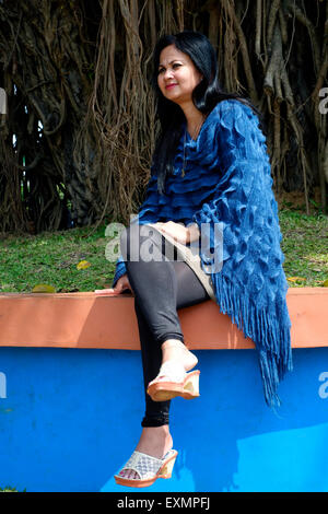 pretty well dressed local female posing in front of tree with large roots in a park in the center of malang java indonesia Stock Photo
