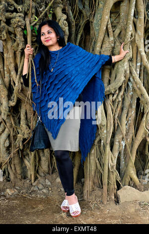 pretty well dressed local female posing in front of tree with large roots in a park in the center of malang java indonesia Stock Photo