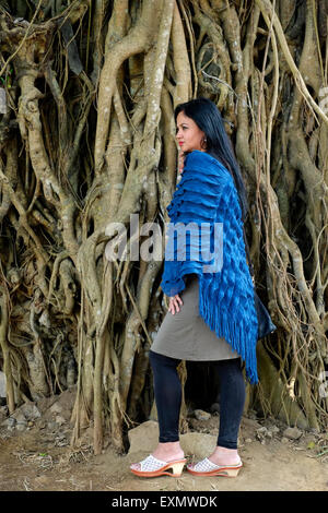 pretty well dressed local female posing in front of tree with large roots in a park in the center of malang java indonesia Stock Photo