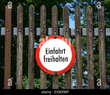 Round German sign on a wooden fence instructs 'Keep entrance clear' - Einfahrt freihalten Stock Photo