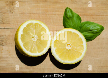 cut lemon with basil leafs on a wooden desk Stock Photo