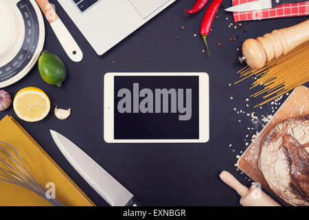 Kitchen or restaurant and food hero header. Kitchen items with copy space on black background with tablet pc Stock Photo