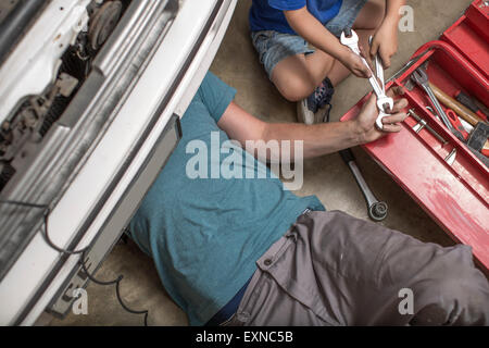 Son helping father in home garage working on car Stock Photo