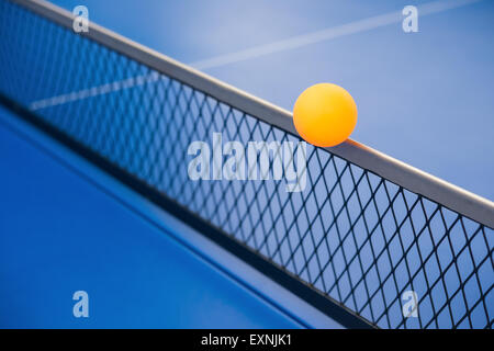 yellow ball hits the racket on a blue pingpong table Stock Photo