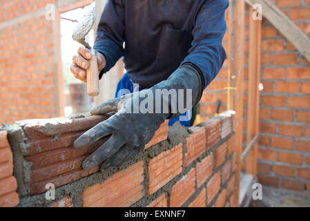 Worker building masonry house wall with bricks Stock Photo