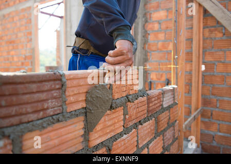 Worker building masonry house wall with bricks Stock Photo