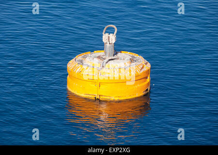 Yellow mooring buoy floating on blue sea water Stock Photo