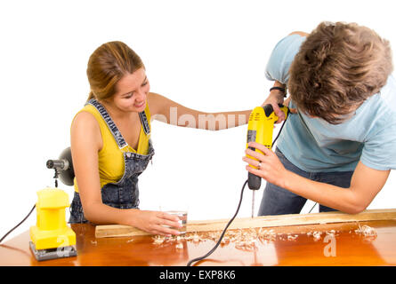 Couple renovating together as man using power drill on wooden surface with girlfriend standing beside him holding his back Stock Photo