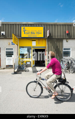 A cyclist rides by the Trail Bike Hire shop on the Camel Trail in Padstow Cornwall UK Stock Photo