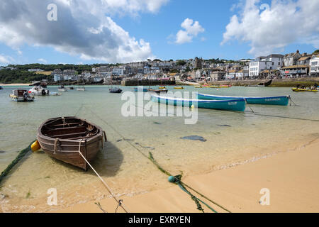 St Ives, Cornwall, UK:  Wooden rowing boat and Gig rowing boats in St Ives harbour with beach in foreground. Stock Photo