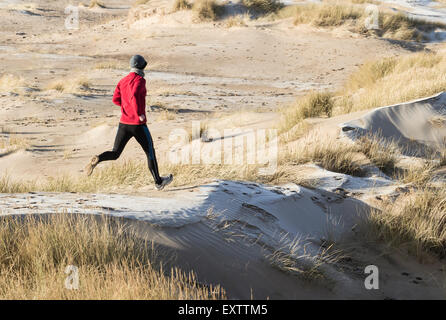 Mature man running on sand dunes covered in frost at Seaton Carew on the north east coast of England. UK Stock Photo