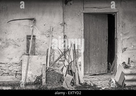 Farm tools near wall of old shed. Black and white photo. Stock Photo