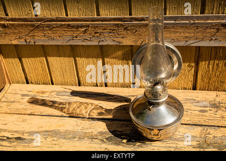 old kerosene lamp stands on wooden surface, outdoors Stock Photo