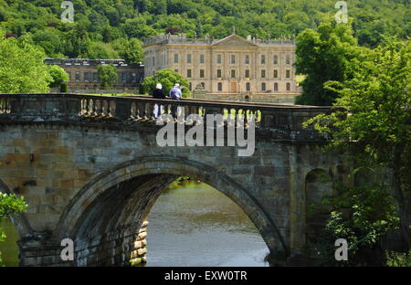 Visitors to Chatsworth House on an arched bridge  on the main approach to the Derbyshire stately home Derbyshire England UK Stock Photo