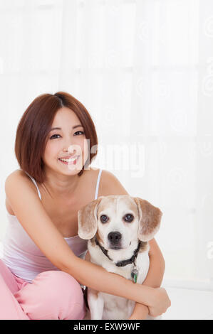 Young woman embracing dog and smiling at the camera, Stock Photo