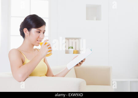 Young woman drinking juice and reading a book, Stock Photo