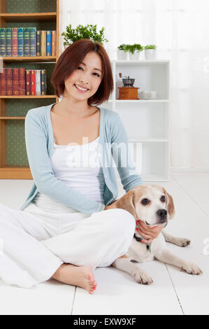 Young woman sitting on the floor with her dog, Stock Photo