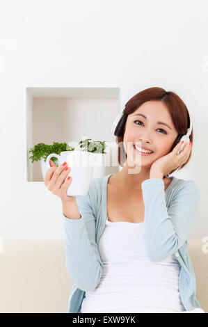 Young woman holding coffee cup and wearing headphone, Stock Photo