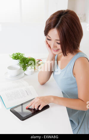 Young woman reading book and touching note pad, Stock Photo