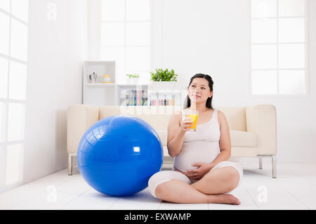 Pregnant woman holding a glass of juice and looking away, Stock Photo