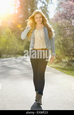 Young woman walking on path in park Stock Photo