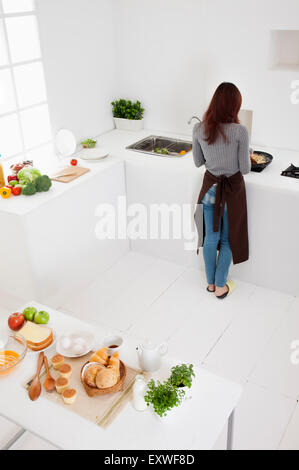 Young woman standing in the kitchen with rear view, Stock Photo
