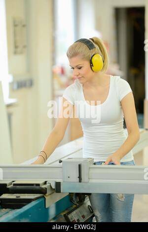 Young woman working in a carpentry on a buzzsaw Stock Photo