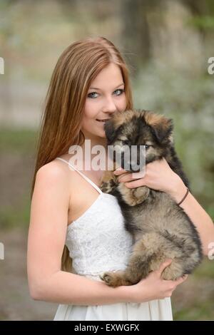 Young woman with a mixed breed dog puppy in garden Stock Photo