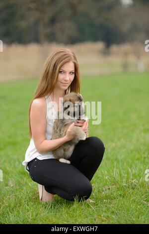 Young woman with a mixed breed dog puppy in garden Stock Photo