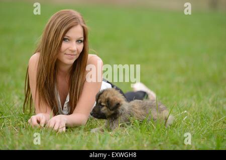 Young woman with a mixed breed dog puppy in garden Stock Photo