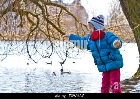 Girl feeding ducks in winter Stock Photo