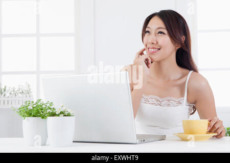 Young woman holding a cup and looking up with smile, Stock Photo