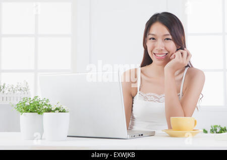 Young woman using laptop and smiling at the camera, Stock Photo