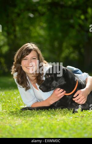 Woman with a black labrador on a meadow, Bavaria, Germany, Europe Stock Photo