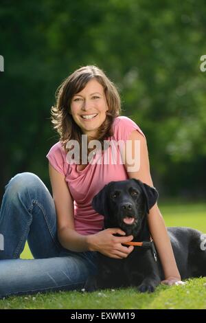 Woman with a black labrador on a meadow, Bavaria, Germany, Europe Stock Photo