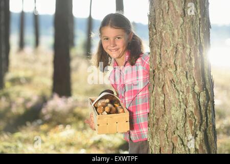 Girl collecting mushrooms in a pine forest Stock Photo