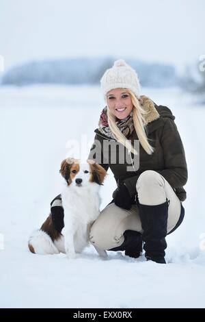 Young woman with a Kooikerhondje dog in snow Stock Photo