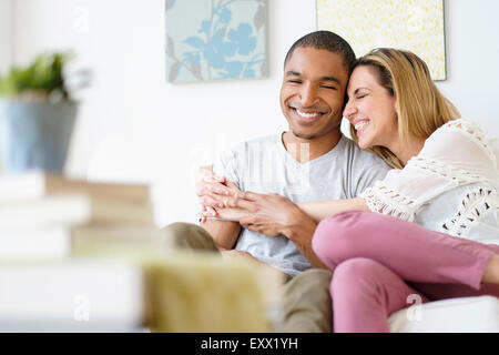 Mid adult couple embracing in living room Stock Photo