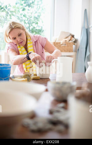 Mature woman making pottery in studio Stock Photo