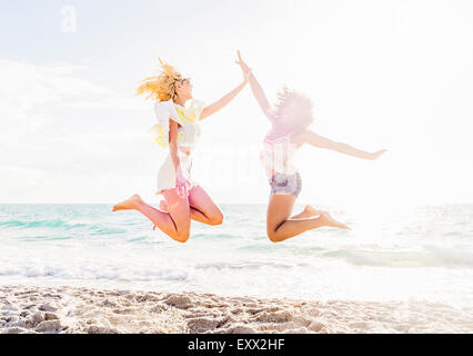 Female friends jumping on beach Stock Photo