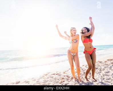 Female friends dancing on beach Stock Photo