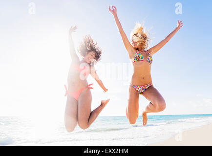 Female friends jumping on beach Stock Photo