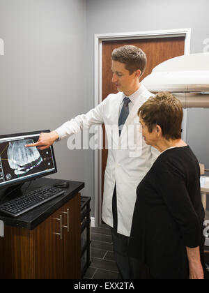 Dentist showing patient x-ray on computer screen Stock Photo