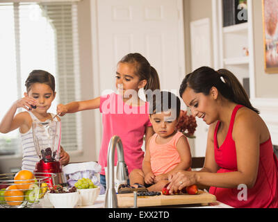 Mother and children (2-3, 6-7, 8-9) preparing fruit cocktails Stock Photo