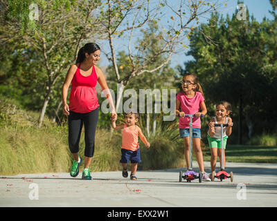 Pregnant mother and children (2-3, 6-7, 8-9) walking outdoors Stock Photo